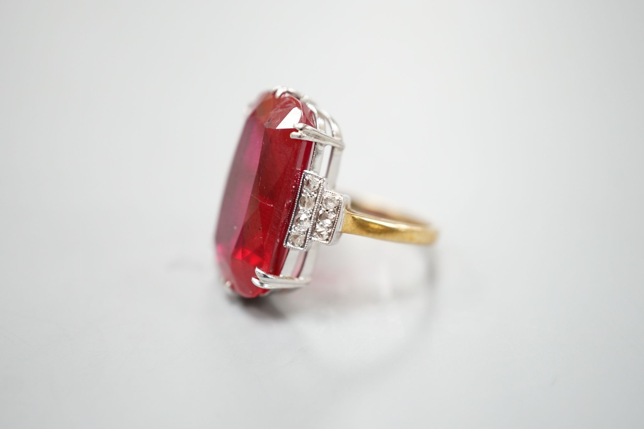 A yellow metal and large synthetic ruby set dress ring, with rose cut diamond set stepped shoulders, size L/M, gross weight 8 grams.
